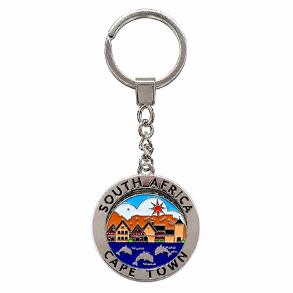 A silver metal keychain featuring a circular charm engraved with 'SOUTH AFRICA' and 'CAPE TOWN' and decorated with colorful enameled artwork of Cape Town's skyline, mountains, and harbor.